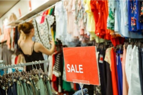 sale sign in front of woman browsing clothes in resale store